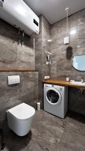 a bathroom with a toilet and a washing machine at Apartments in Grani in Dnipro