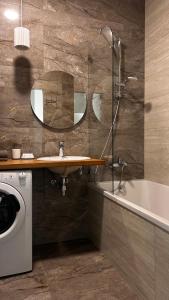 La salle de bains est pourvue d'un lavabo, d'une baignoire et d'un lave-linge. dans l'établissement Apartments in Grani, à Dnipro