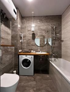 a bathroom with a washing machine and a bath tub at Apartments in Grani in Dnipro