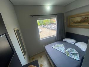a small bedroom with a bed and a window at Maranata Hotel in Aparecida