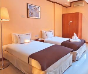 a hotel room with two beds and a lamp at SCN City Hotel Rayong in Ban Chang