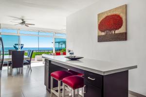 a kitchen with a counter with red chairs and a dining room at Villa San Valentin 48 - Playa Arcangel in Rosarito