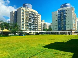 two tall buildings with a grass field in front at Nautilus Vigia das Marés - Penha - SC in Penha