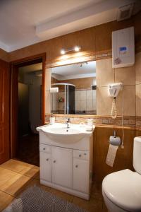 W łazience znajduje się umywalka, toaleta i lustro. w obiekcie Pokoje Przy Plaży w mieście Mielno