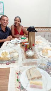 um homem e uma mulher sentados à mesa com comida em Lulle Hostel em São Paulo