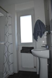 uma casa de banho branca com um lavatório e uma janela em Belle chambre exposée Sud em Le Havre