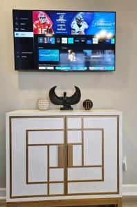 a flat screen tv on a wall with a white cabinet at Chic Oasis: 3BR, 2BA, Private Deck in Charleston