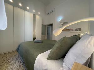 ein Schlafzimmer mit einem Bett mit einer grünen Decke und Kissen in der Unterkunft Alloggio dei Volsci in Nettuno