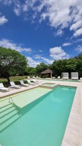 a large swimming pool with chairs and a blue sky at Las Dalias in Villa Las Rosas