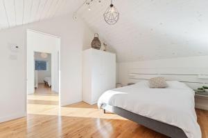 Dormitorio blanco con cama y pasillo en Stillness on the Shore - Fabulous family cottage en Parry Sound