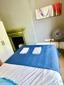 a blue and white bed in a room with a fan at Elegant 2 Bedroom Apartment in Central London in London