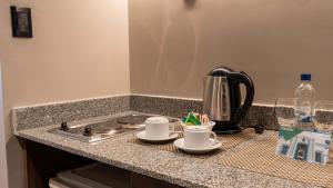 a kitchen counter with two cups and a tea kettle at Garden Park Hotel in San Miguel de Tucumán