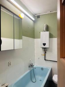 a bathroom with a blue tub and a mirror at Traditional White House with private garden and free parking in Tomaszów Mazowiecki