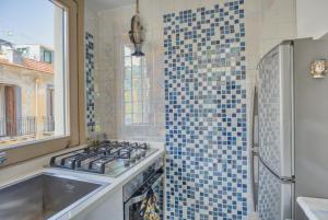 a kitchen with a stove and a blue tiled wall at Devalù casa del mare in Cefalù +39 photos