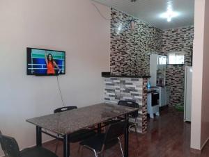 Habitación con mesa, sillas y TV en la pared. en Apartamento Mobiliado - Wi-Fi, en Boa Vista