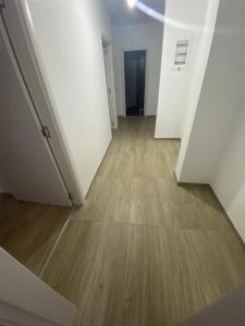 apartment gjilan في Gnjilane: ممر فارغ بجدران بيضاء وارضيات خشبية
