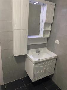 bagno con lavandino bianco e specchio di apartment gjilan a Gnjilane