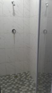 ダーバンにあるIqhayiya Guest Houseのタイルフロアのガラスドア付きのシャワーが備わります。
