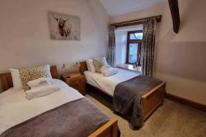 um quarto com 2 camas e uma janela em West Nymph Holiday Cottages Leafy Nook em South Tawton