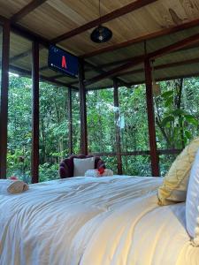 Puyu Glamping في Tarqui: سرير أبيض كبير في غرفة بها أشجار