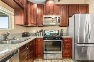 una cucina con mobili in legno e un frigorifero in acciaio inossidabile di The Unicorn House - 9 min Park entrance - Pool, Outdoor Dining a Joshua Tree Altre 35 foto