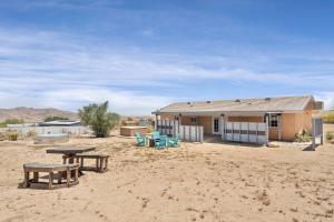 una casa nel deserto con un tavolo da picnic e panchine di The Unicorn House - 9 min Park entrance - Pool, Outdoor Dining a Joshua Tree