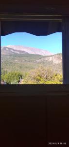 a view of a mountain from a window at BALCON CORDILLERANO in El Bolsón