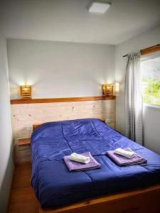 a bedroom with a blue bed with two towels on it at BALCON CORDILLERANO in El Bolsón