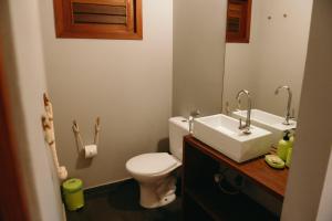 a bathroom with a white toilet and a sink at Flor da Mata in Pipa