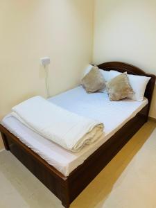 a bed with white sheets and pillows on it at Small Room shared bath with beach access for single person or short stay couplesغرفة صغيرة مع حمام مشترك مع إمكانية الوصول إلى الشاطئ لشخص واحد أو للأزواج الذين يقيمون لفترة قصيرة in Ajman 