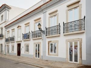een wit gebouw met balkons in een straat bij Casa Apollo Guesthouse in Faro