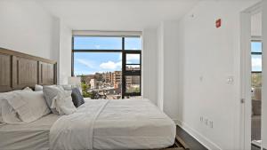 a white bedroom with a large bed and a window at Pure Voyage Shaw in Washington