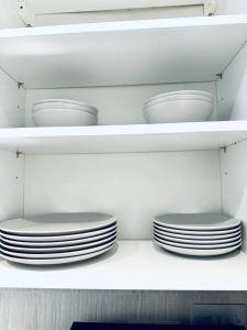 une étagère avec des assiettes et des bols blancs dans une cuisine dans l'établissement Modern 2 bedroom Flat in Balham, à Londres