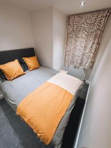 - une petite chambre avec un lit et une couverture orange dans l'établissement Modern 2 bedroom Flat in Balham, à Londres