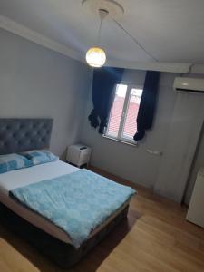 um quarto com uma cama com lençóis azuis e uma janela em 1643 suit apart em Çekirge