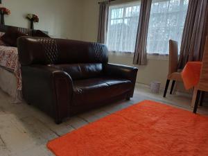 a black leather couch in a living room with an orange rug at 5 On Cologne in Germiston