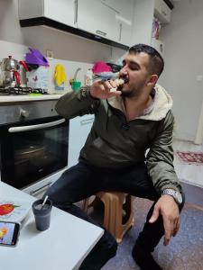 a man sitting in a chair eating food in a kitchen at 1643 suit apart in Çekirge