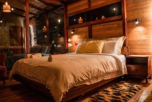 1 dormitorio con 1 cama grande y pared de madera en Puyu Glamping, en Tarqui