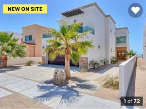 a house with a palm tree in front of it at A Coastal House for Relaxation near Golf Course And Beach Front in Puerto Peñasco