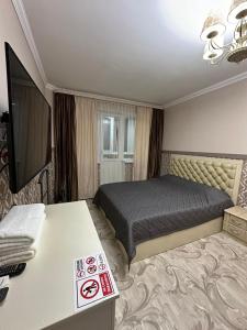 een hotelkamer met een bed en een televisie bij Люкс в центре города in Karagandy