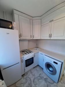een keuken met witte kasten en een wasmachine en droger bij Люкс в центре города in Karagandy