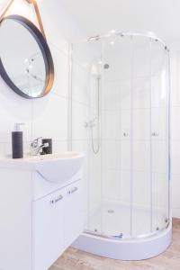 a white bathroom with a shower and a sink at "AGUŚ" Komfortowe i nowczesne domki w cichej okolicy niedaleko plaży in Ostrowo