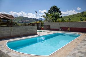 a swimming pool in a backyard with a wall and mountains at Hotel Águas Lindas in Itamonte