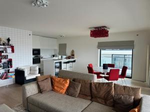 uma sala de estar com um sofá e uma mesa com cadeiras em Open zicht op stad Oostende en zee/strandzicht, groot zuidterras, 3 slpks, 125m², dubbele garage em Oostende