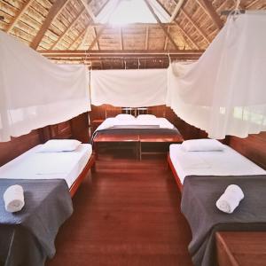 a room with three beds in a boat at Ecolucerna Lodge Tambopata in Puerto Maldonado