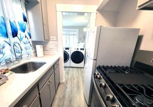 a kitchen with a refrigerator and a washing machine at Beautiful Guesthouse, Sleeps 4 - Kitchen, Private Laundry, AC, Parking, 65' TV, Close to Stores, Restaurants & Beach in Long Beach