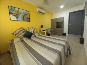 1 dormitorio con cama y pared amarilla en Tu Estancia Guadalajara, en Guadalajara