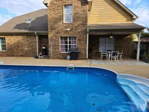 una casa con una piscina blu di fronte a una casa di Spacious, State Line, Private Pool with king Beds a Olive Branch