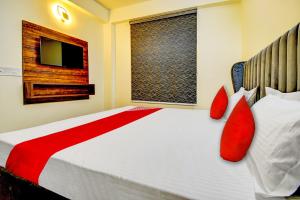 a bedroom with a bed with red pillows and a window at Flagship Hotel White Hut in Delhi