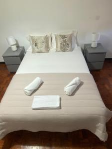 a white bed with two white slippers on it at Quarto Alameda in Lisbon